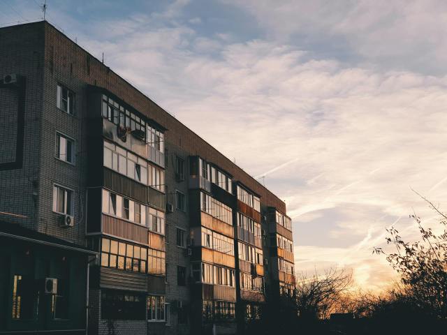 A city apartment building with moody sky at sunset, highlighting urban life.