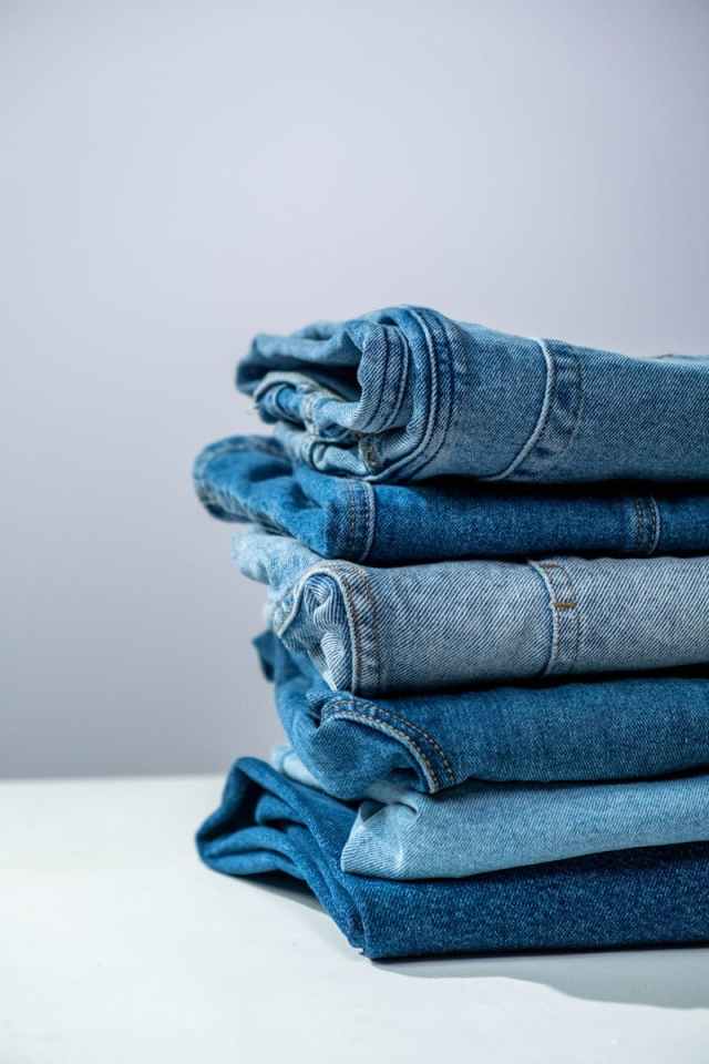 Neatly folded blue denim jeans stacked on a white surface, perfect for fashion or retail themes.