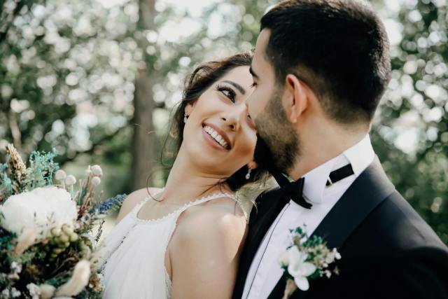 A joyful bride and groom share a loving moment in an outdoor setting, captured beautifully.