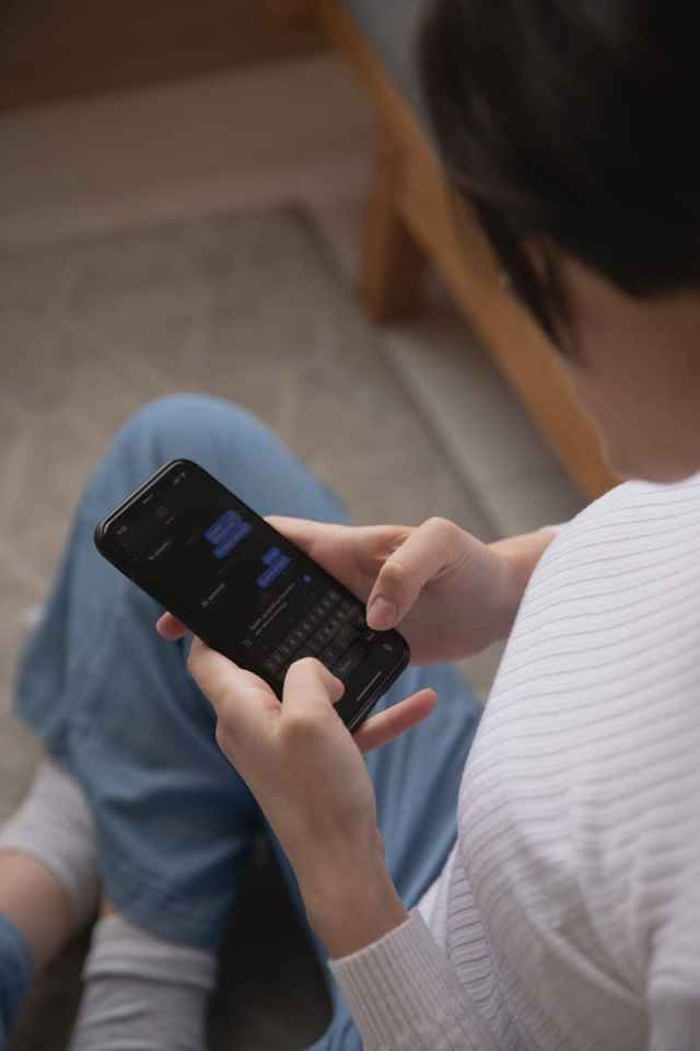 A woman using a smartphone to text, captured from above, indoors setting.
