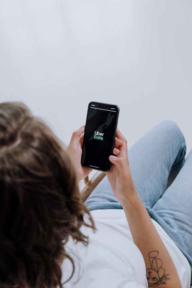 Overhead view of a person using Uber Eats app on a smartphone, showcasing modern technology integration.