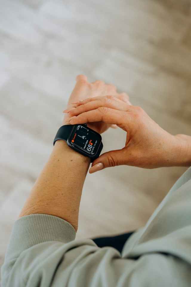 Person interacting with a smartwatch, measuring fitness and heartbeat indoors.