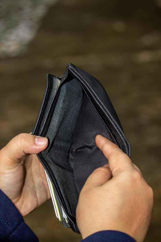 A close-up image of an empty leather wallet held by two hands, symbolizing financial challenges.