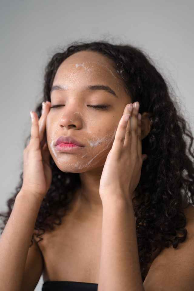 A serene moment of a young woman cleansing her face with facial wash in a skincare routine.