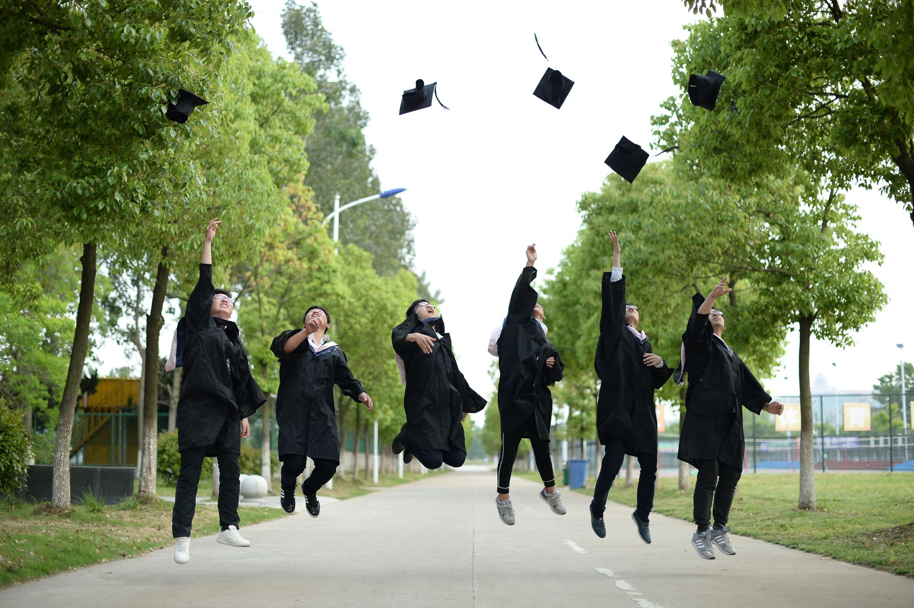 graduates celebrating outdoors with cap toss