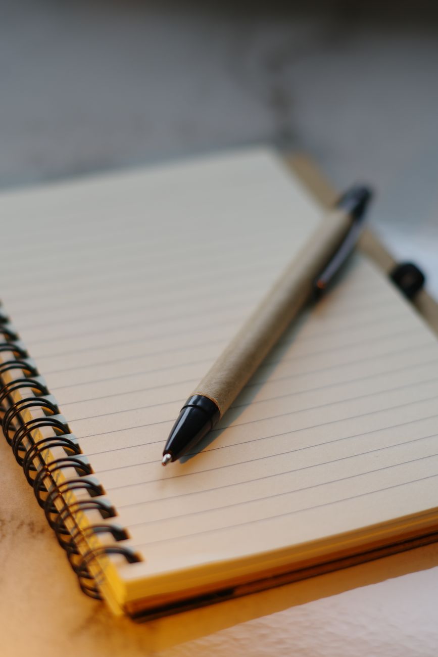 elegant pen resting on blank spiral notebook