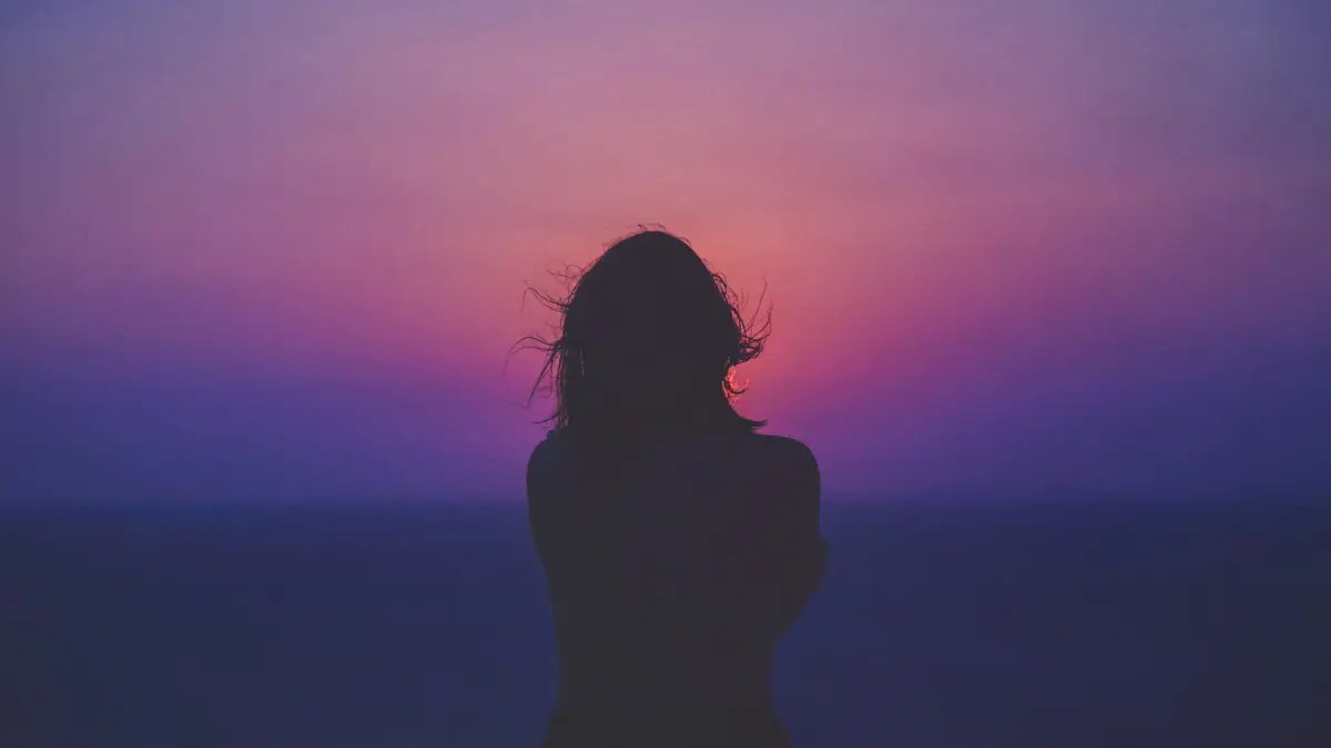 Woman looking into evening sky at dusk