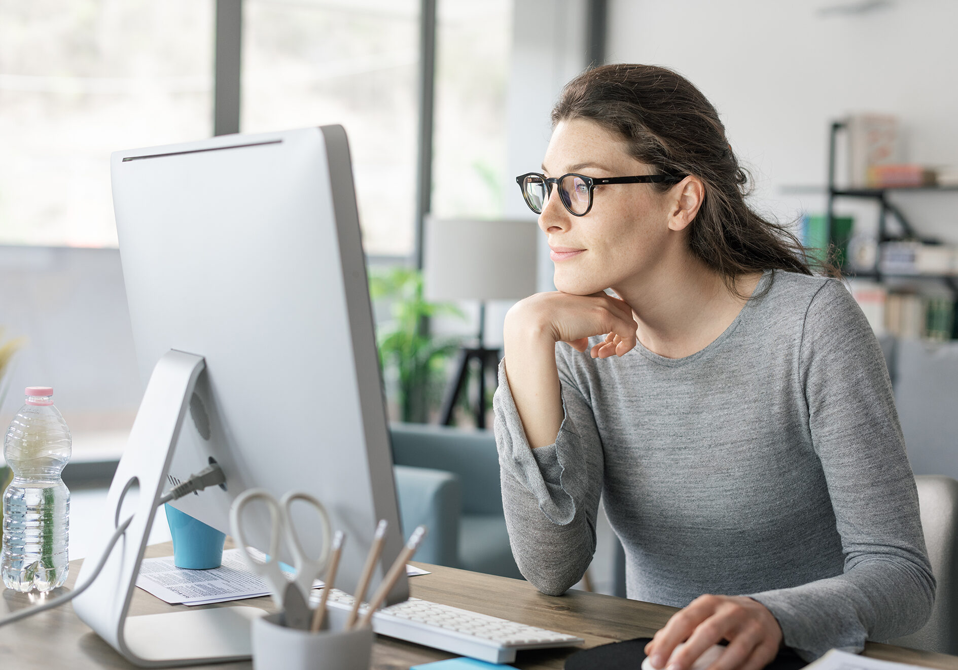 Professional woman sitting at desk and connecting with her computer, she is working from home