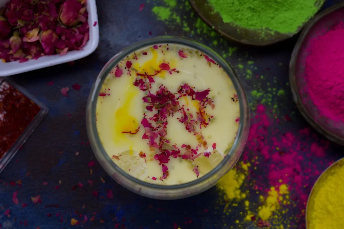 Thandai spice paste being blended with soaked almonds, fennel, and peppercorns before straining into cold milk