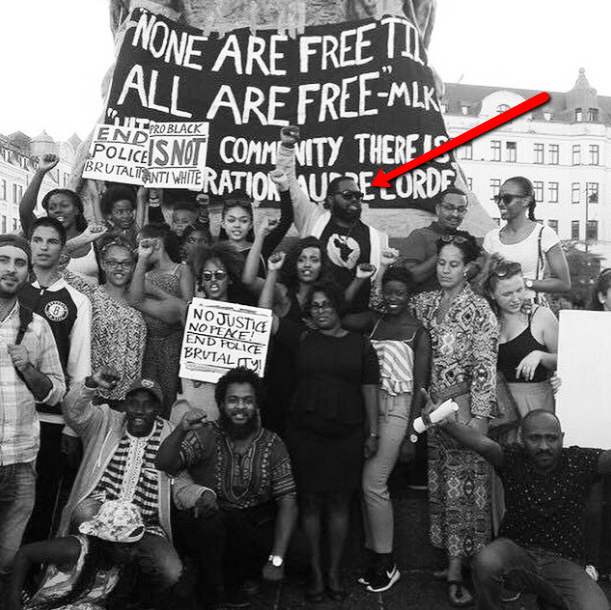 Momodou Malcolm Jallow vid pilen, där syns också andra anti-svenskar. “Afrosvenskarnas forum för rättvisa i Malmö” demonstrerar med skyltar och banderoller på… engelska i Malmö, Sverige.