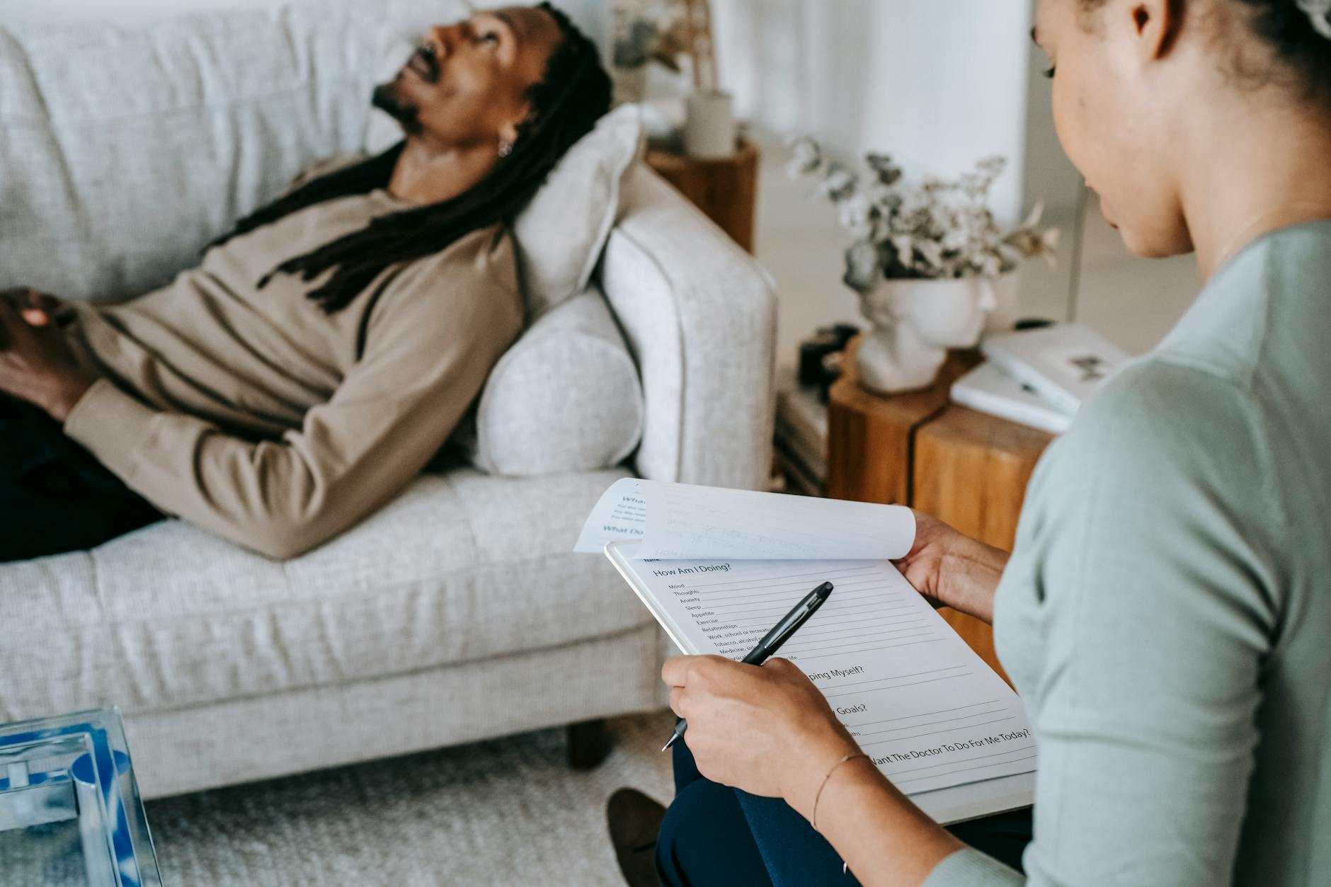 crop black woman with questionnaire interacting with boyfriend on couch
