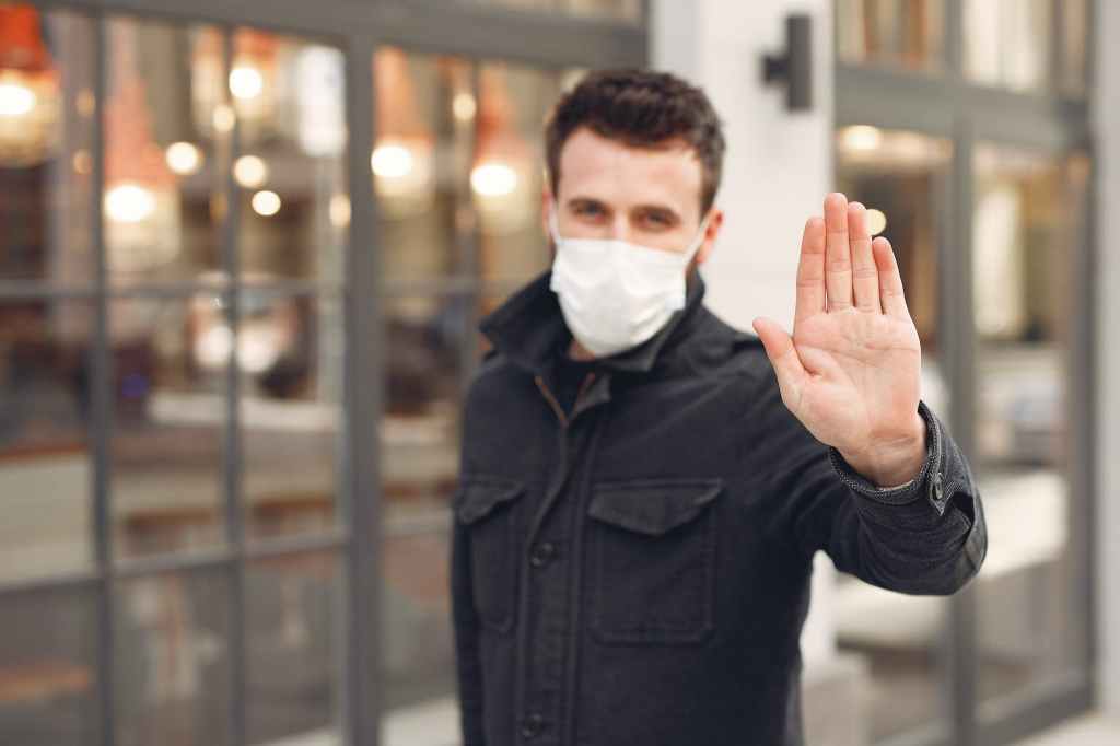 concerned young man in medical mask on urban street during coronavirus pandemic