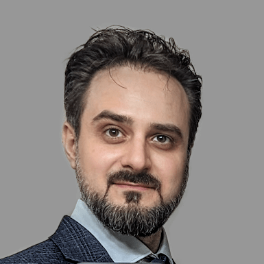 A professional headshot of Sebastian Stanisor, a qhite man with brown hair and a styled, trim, brown beard.