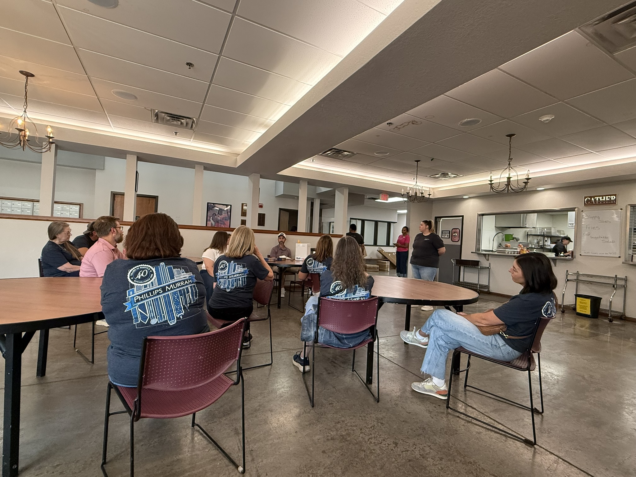 Group of volunteers in a cafeteria listening to a speaker