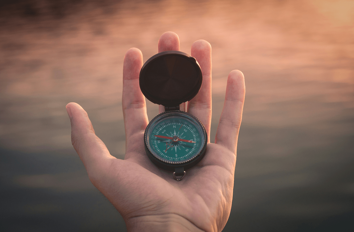 An open hand holds a compass for navigational purposes