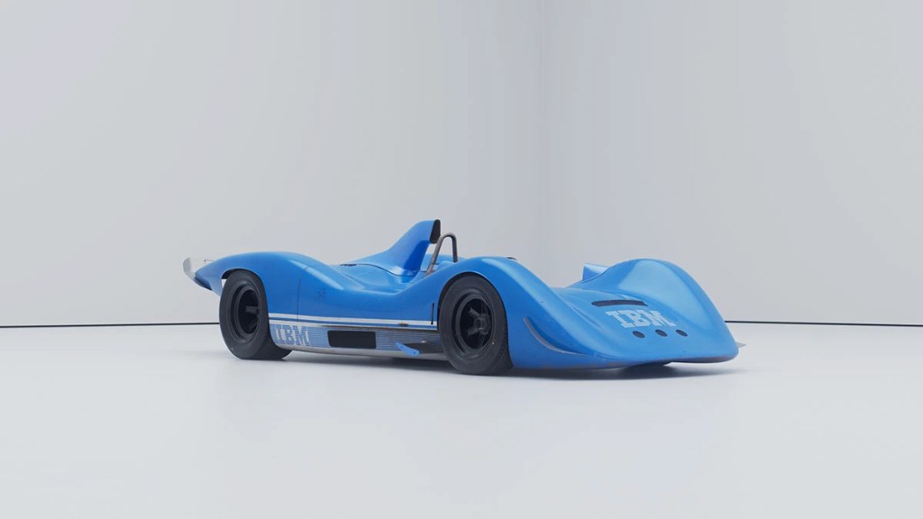 Render hiperrealista de un coche de carrera de color azul con detalles de diseño distintivos, en un fondo blanco simple.