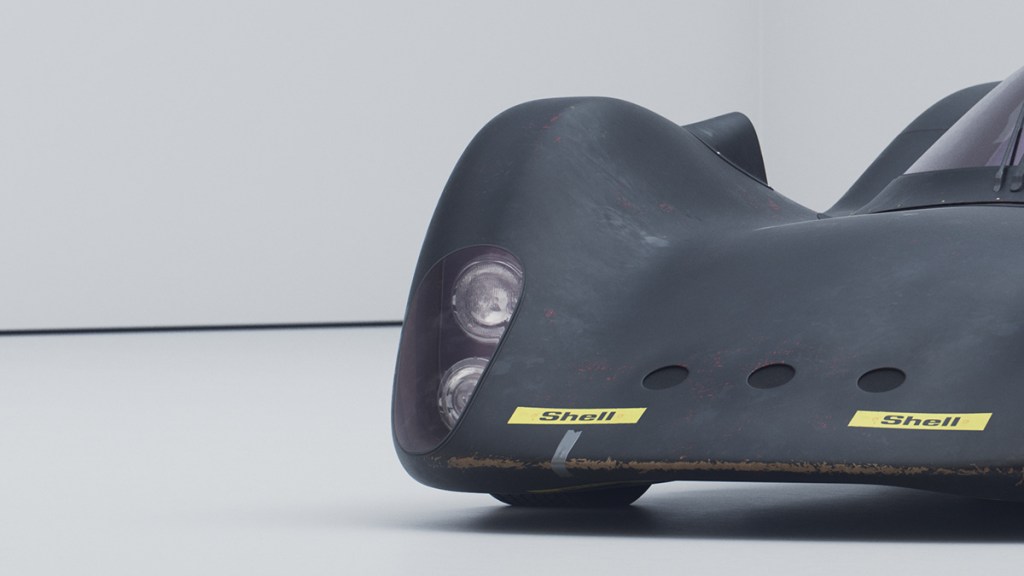 Detalle de un automóvil de carrera con un diseño aerodinámico, mostrando su parte frontal y luces delanteras, sobre un fondo blanco.