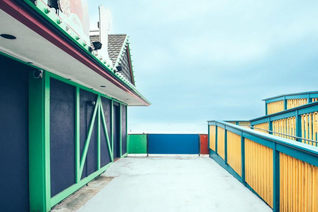 Vista de un pasillo al aire libre con paredes de colores brillantes y un cielo nublado de fondo.