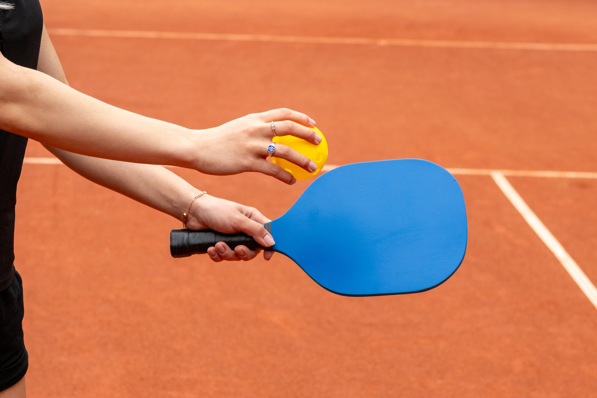 A woman prepares to serve from the right. Singles pickleball follows the same serving rules as doubles pickleball!
