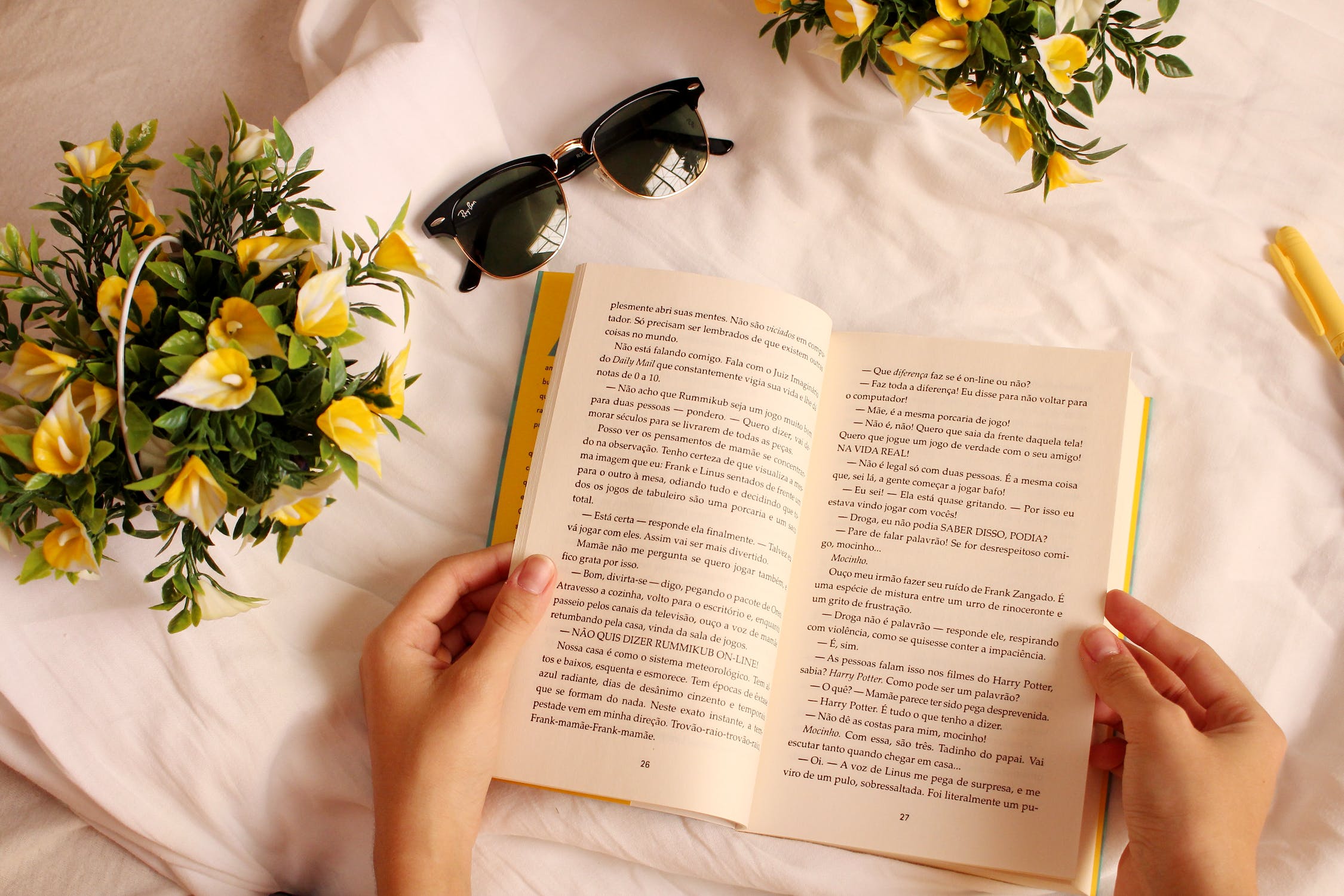 open book against white sheets with lemon yellow flowers.