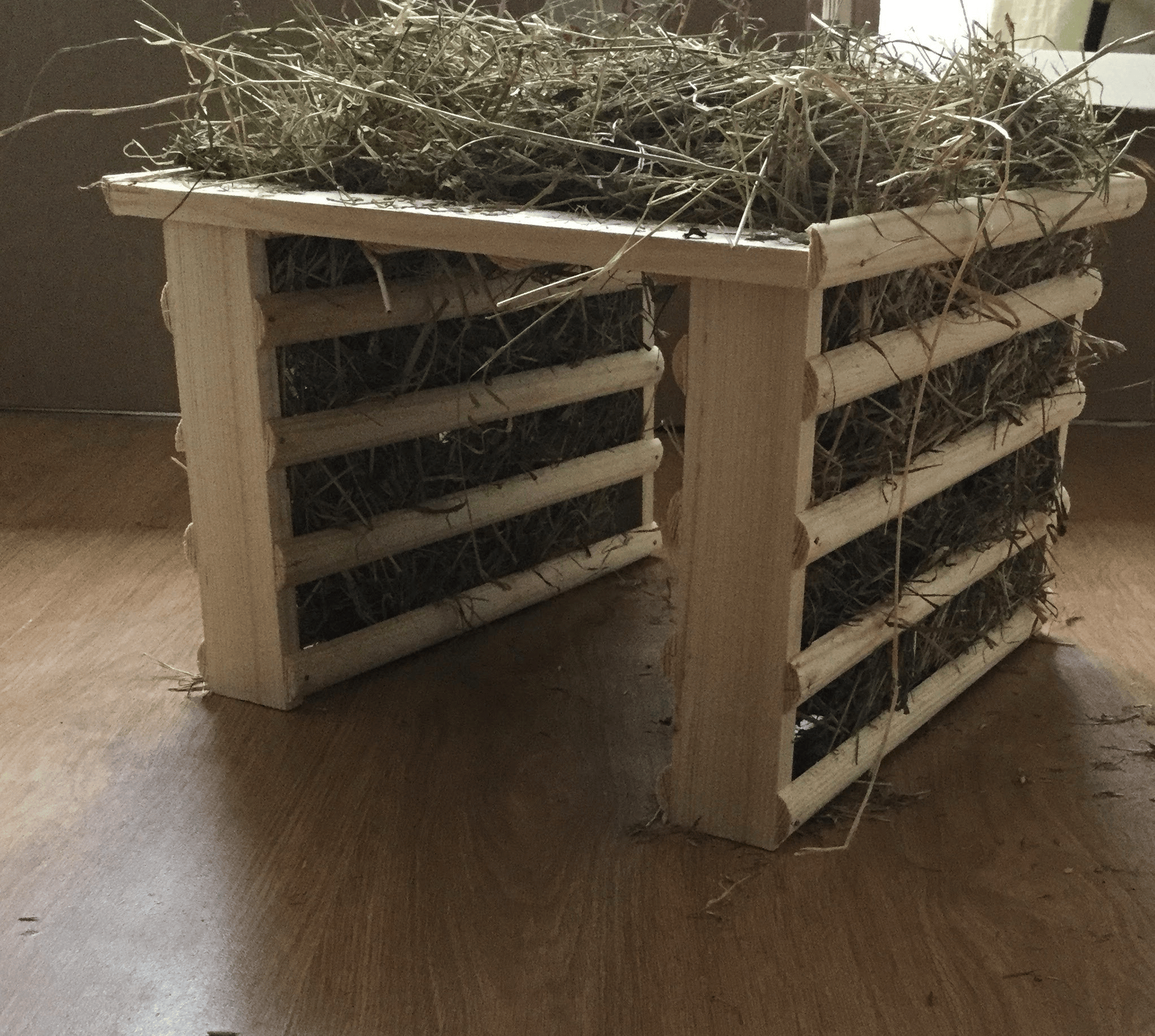Handmade wooden hay rack filled with hay for guinea pigs