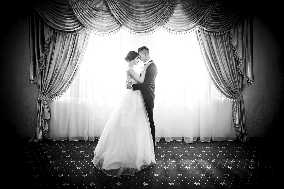 Bride and groom standing together near a window