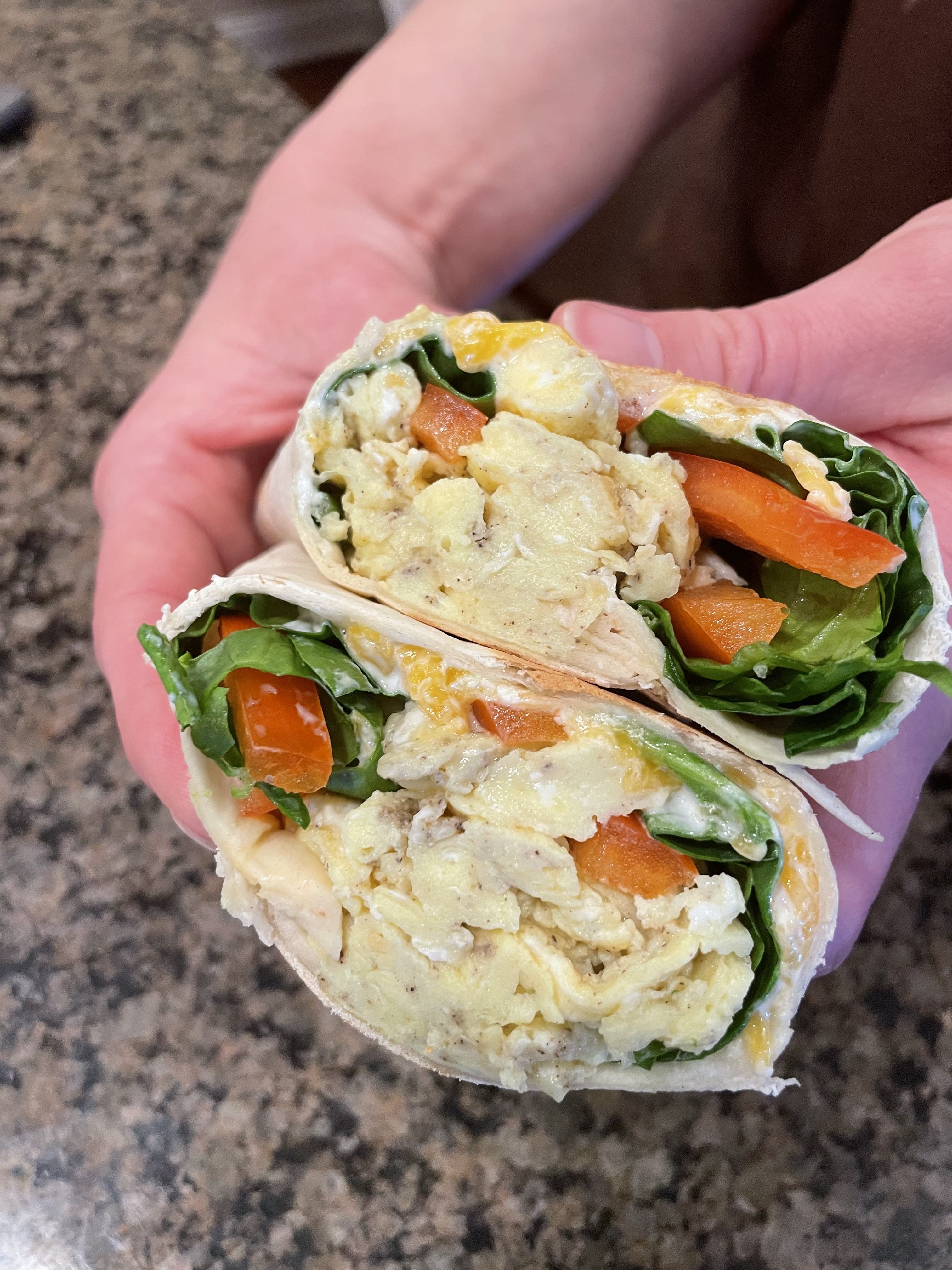 Easy breakfast burritos filled with eggs, sausage, cheese, and colorful vegetables, wrapped and ready to eat.