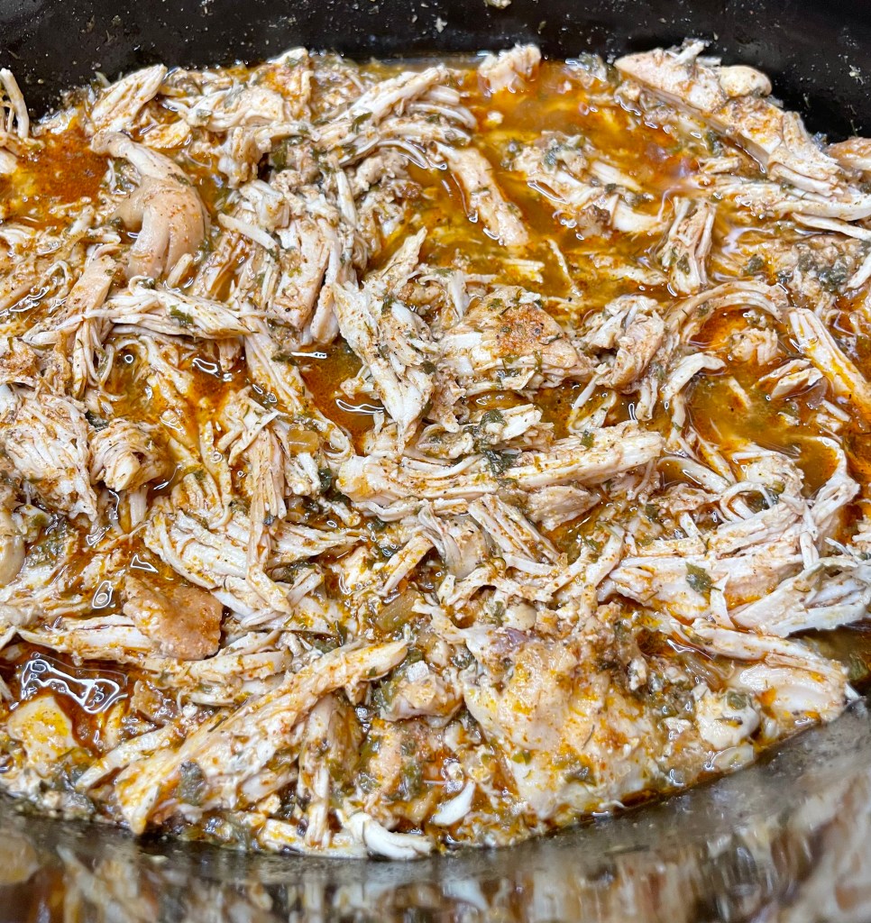 Shredded cool ranch-seasoned chicken in a crock pot, ready to serve in tacos or wraps