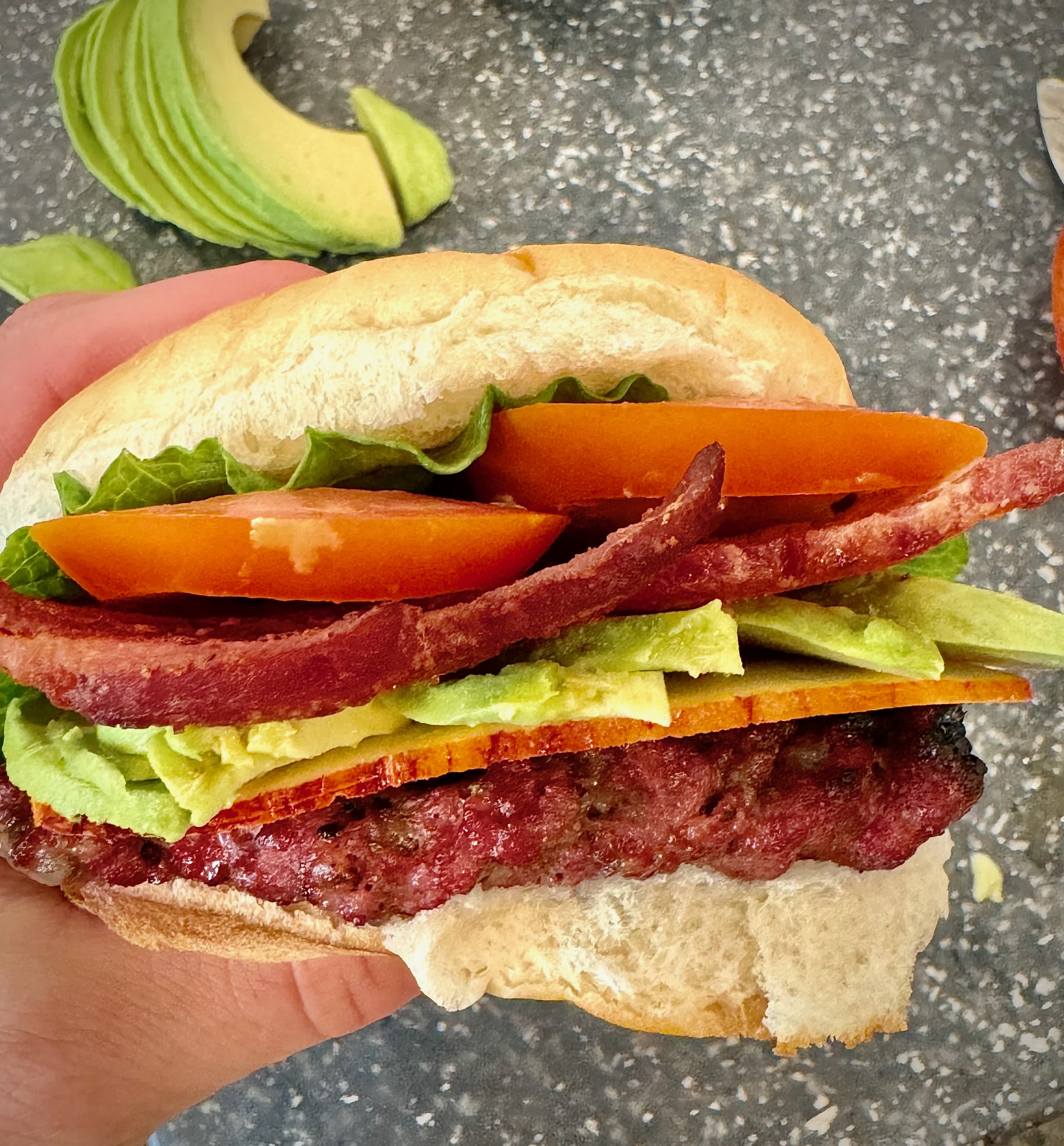 Juicy avocado ranch burger with pepper jack cheese, tomato, and pickles on a toasted bun.