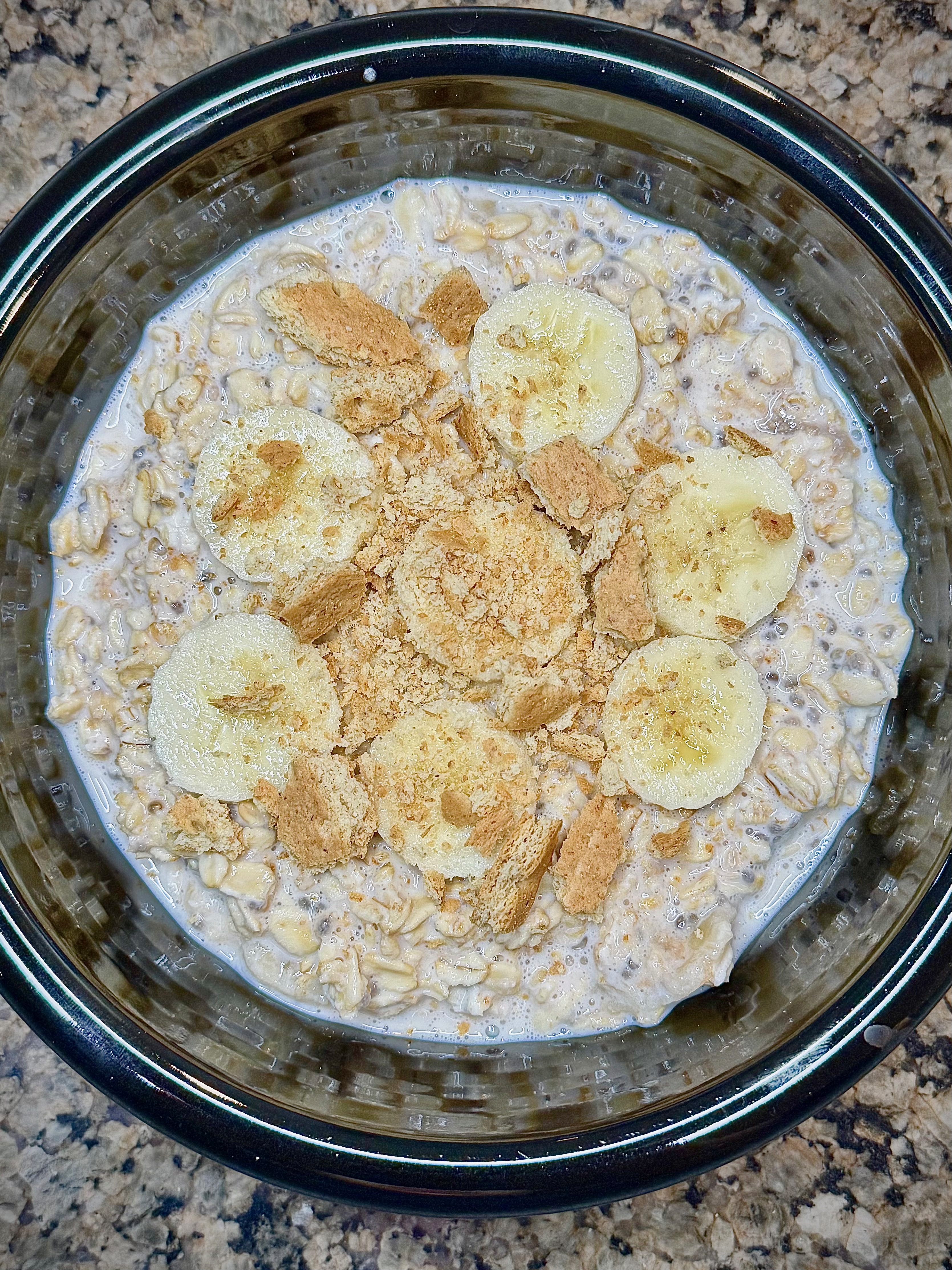 Jar of creamy banana cream pie overnight oats topped with banana slices and graham cracker crumbs