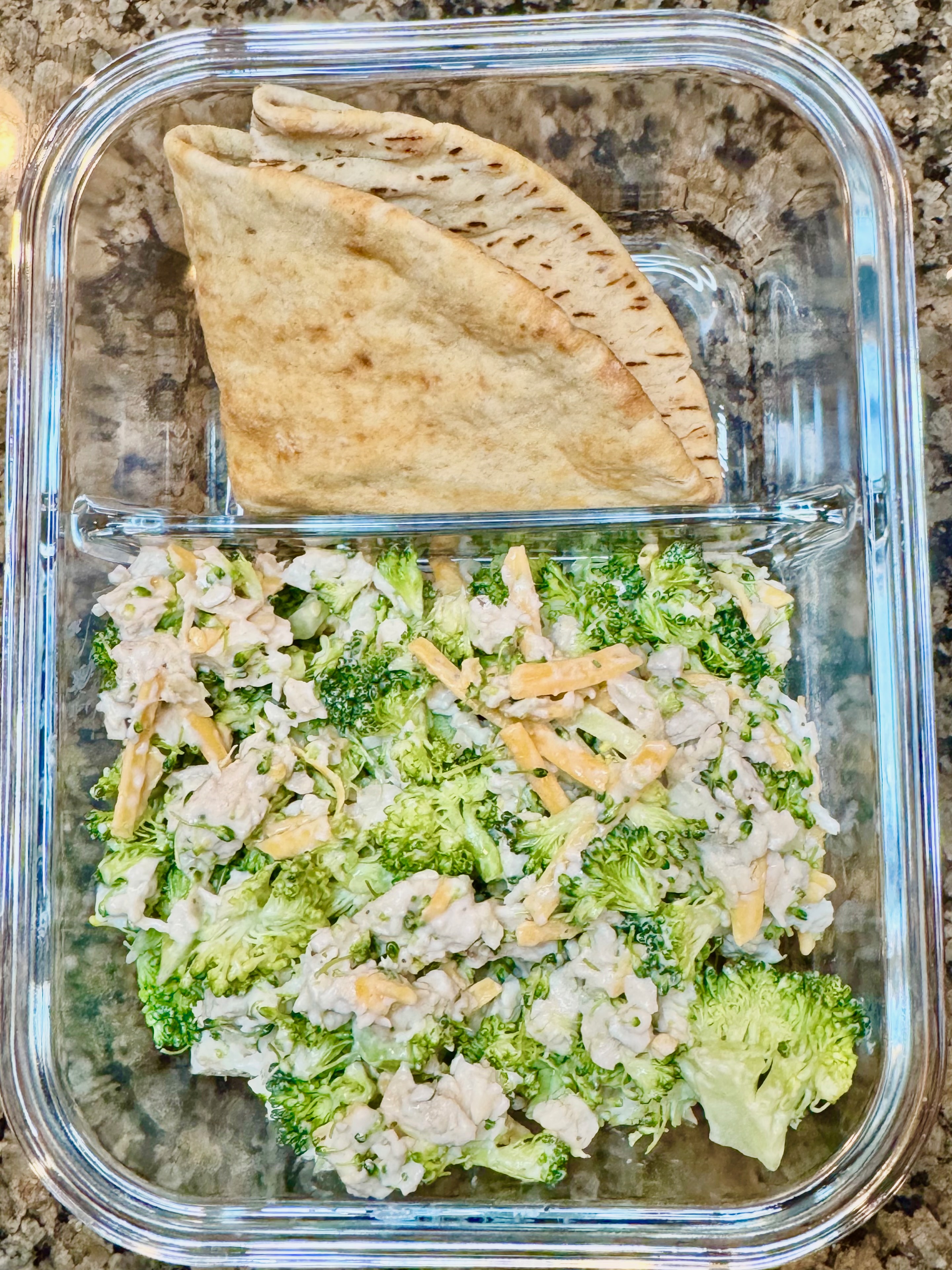A broccoli chicken and ranch salad served with a pita, featuring tender chicken, fresh broccoli, shredded cheese, and creamy ranch dressing.