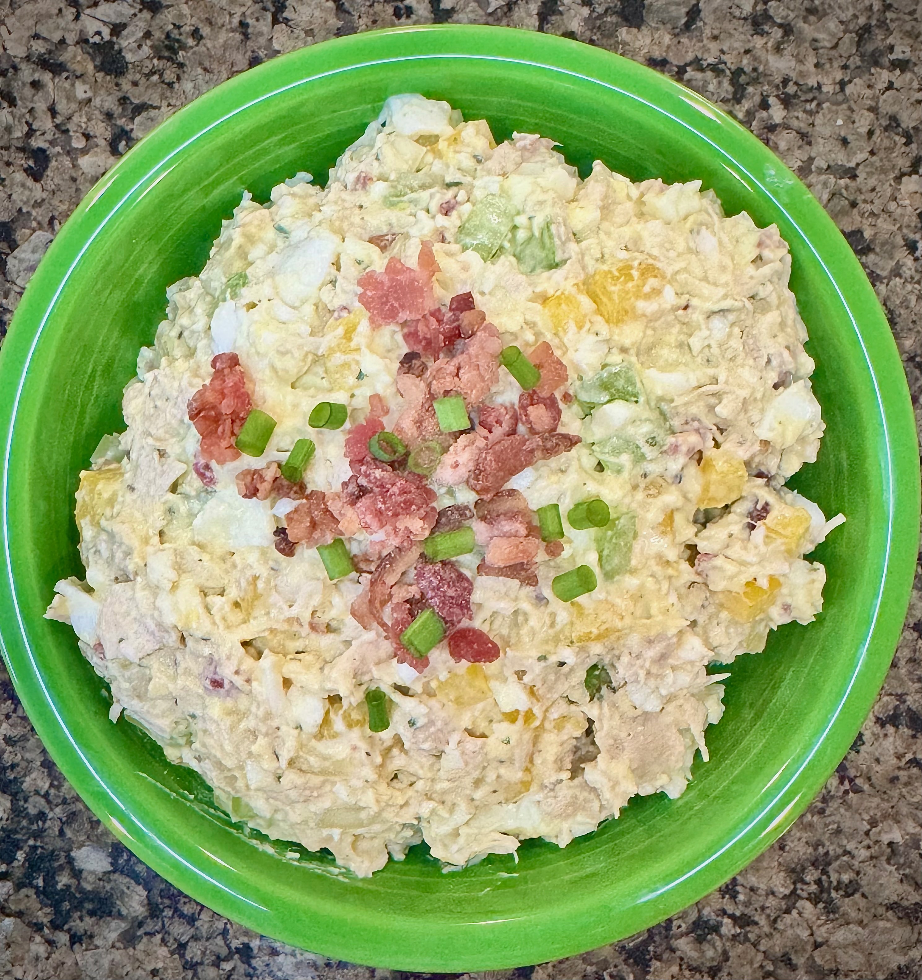 Loaded Chicken Egg Salad in a green bowl topped with bacon bits and sliced green onion.