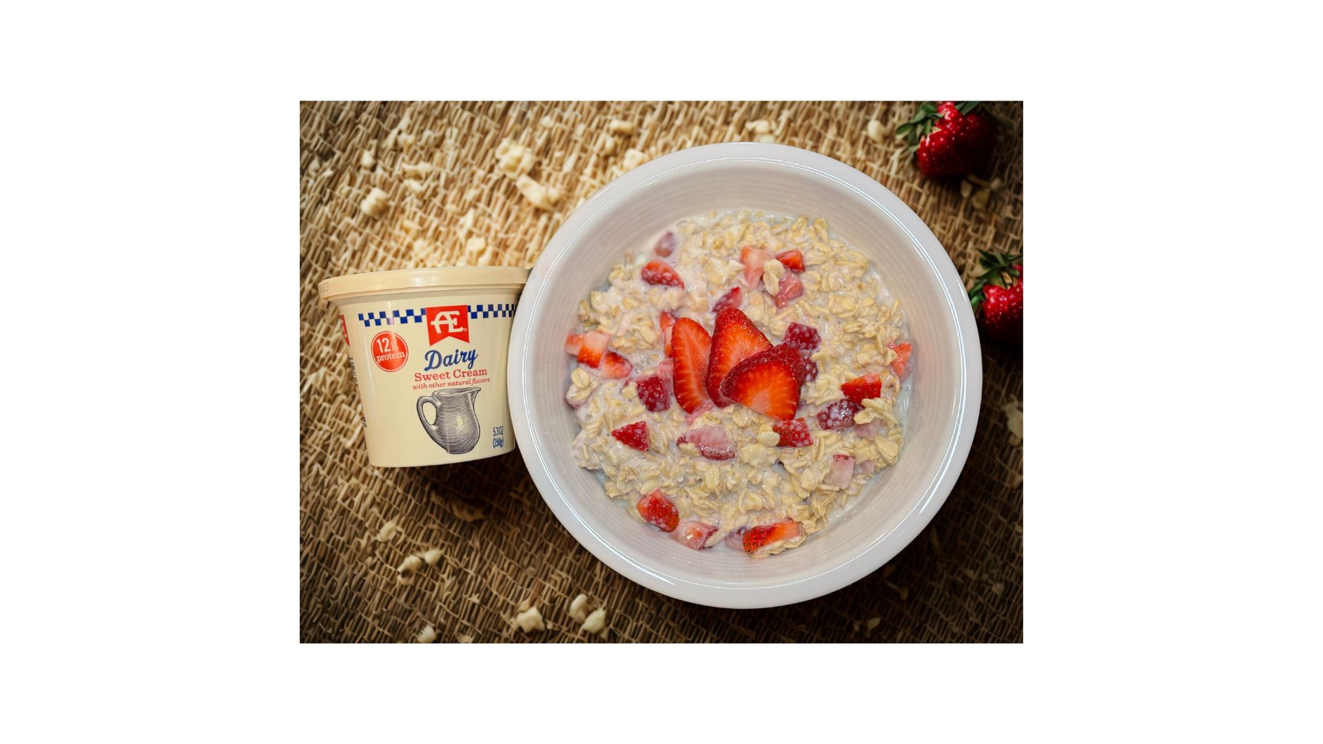 Strawberries and Cream Overnight Oats in a white bowl with a sweet cream yogurt next to it.