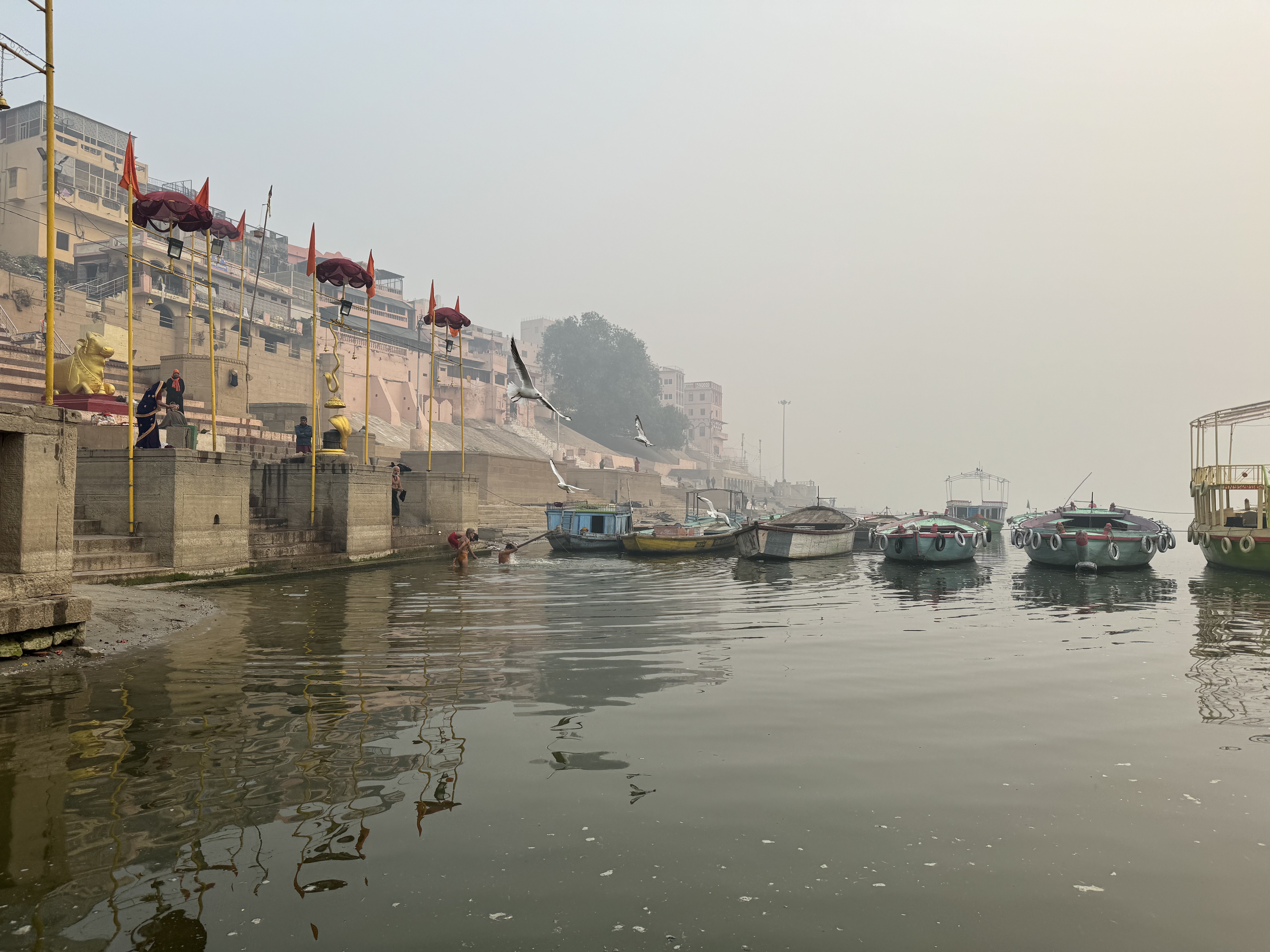 A quiet misty view along the Ganges in Varanasi, with boats beside the ghats