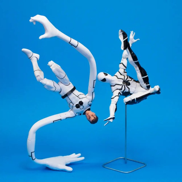Two action figures in dynamic poses on a blue background, one figure appears to be twisting while the other is balancing on a stand.