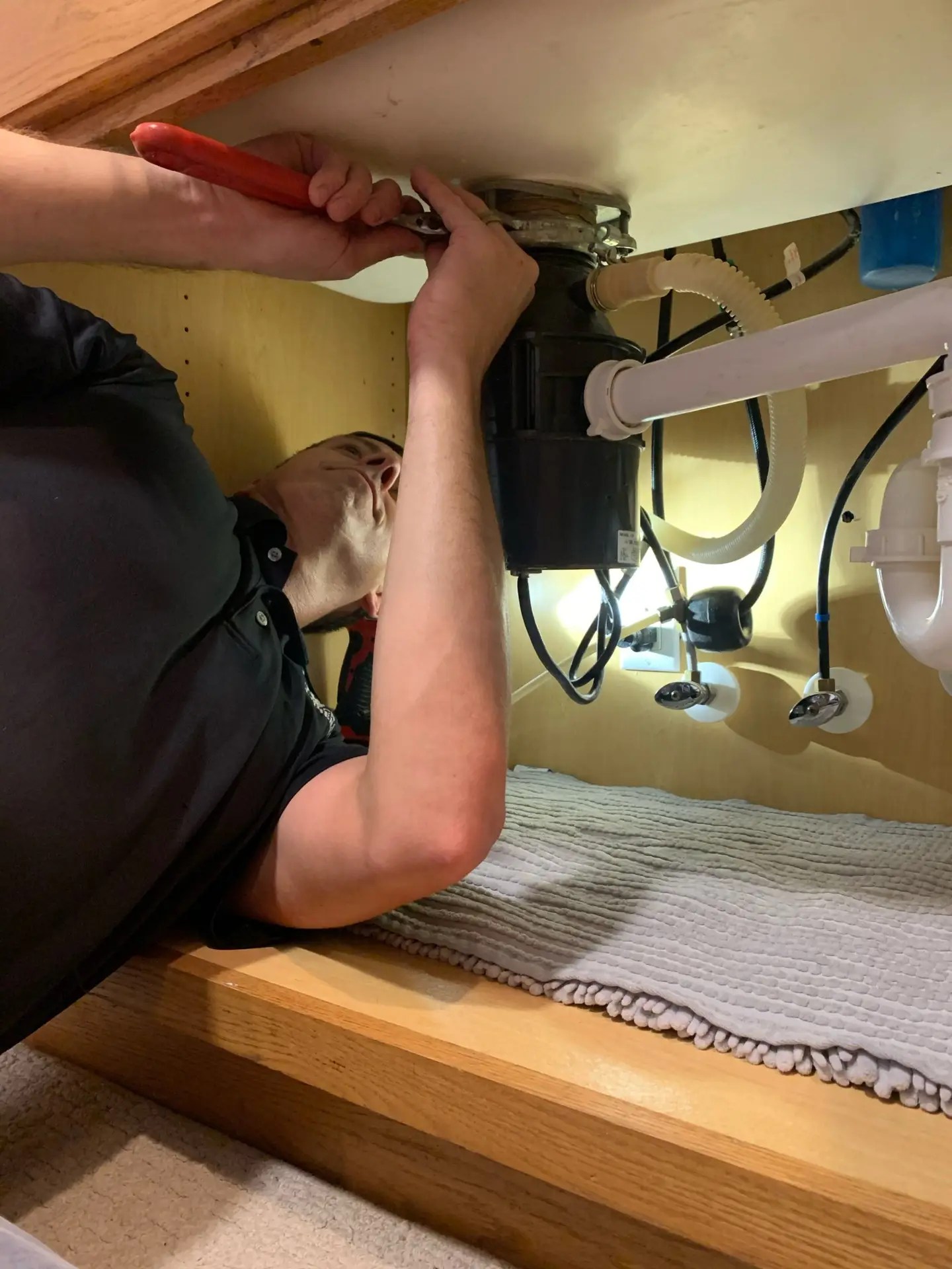 Plumber installing a garbage disposal under kitchen sink