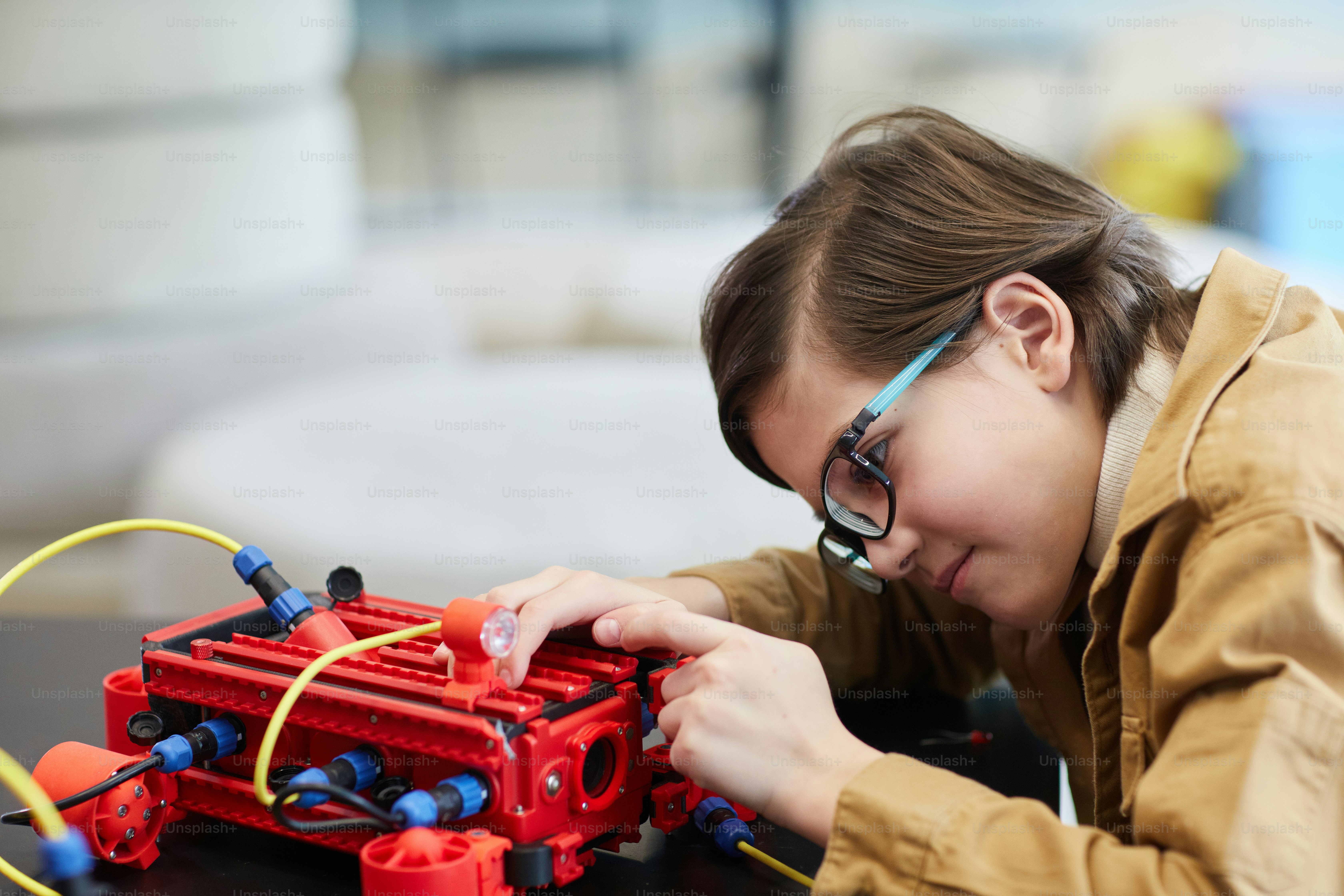 Side View Portrait Of Cute Boy Building Robotic Machine While Enjoying