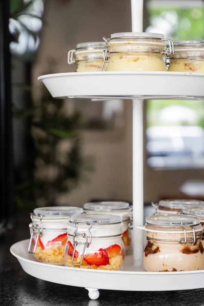 Custom-packaged artisanal sweet treats and elegant glass jars on The Trolley catering display.