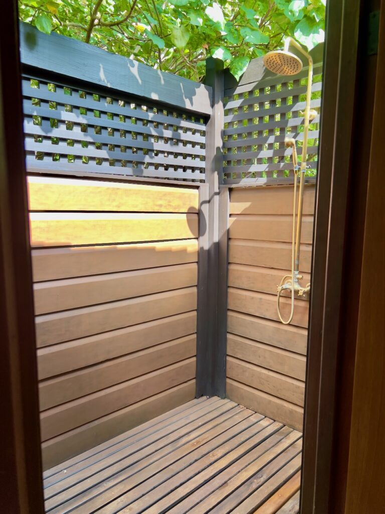 Outdoor shower surrounded by greenery.
