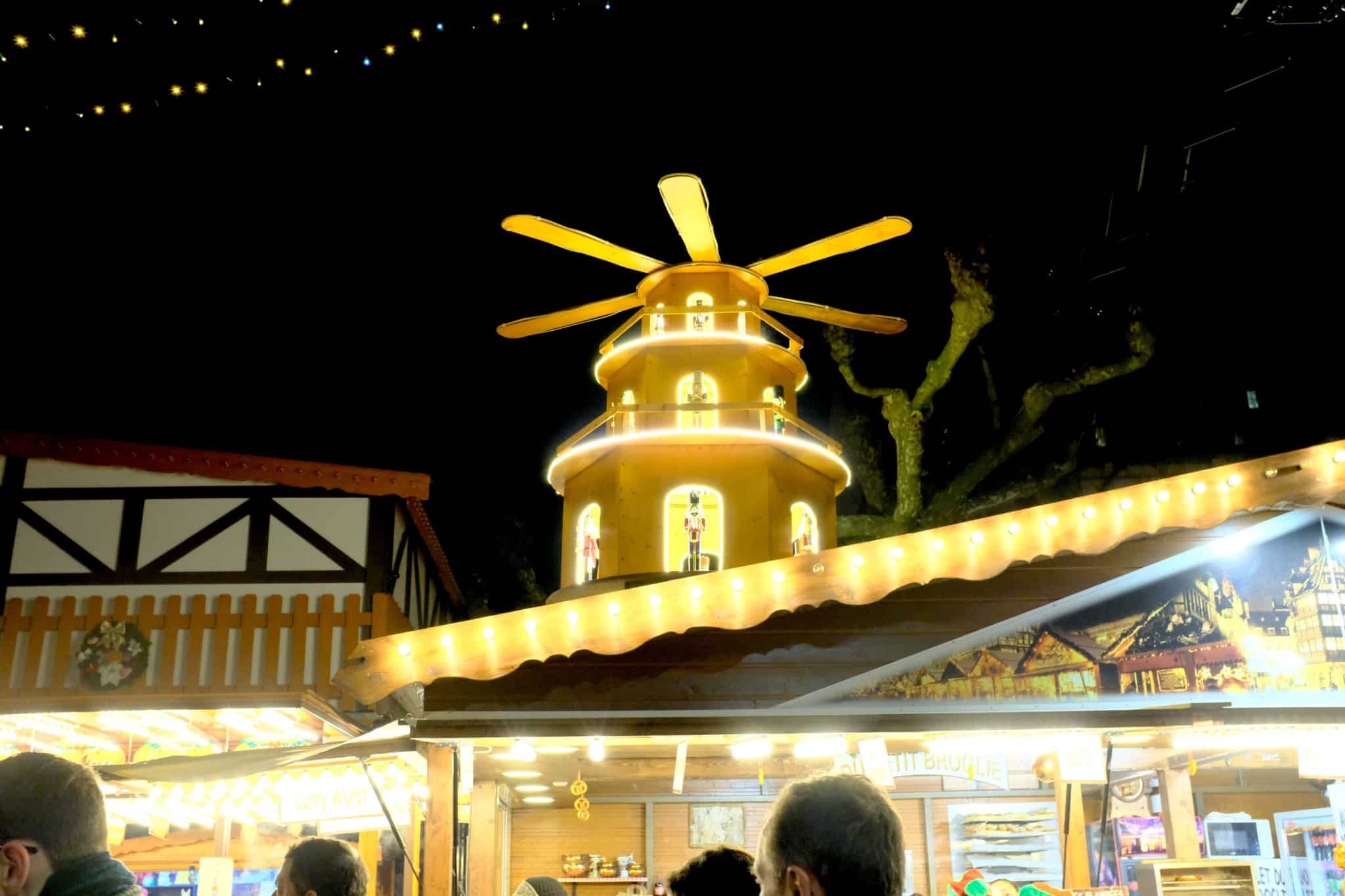 Une pyramide de Noël illuminée au marché, avec des figurines visibles à travers les fenêtres, tournée par la chaleur des bougies.