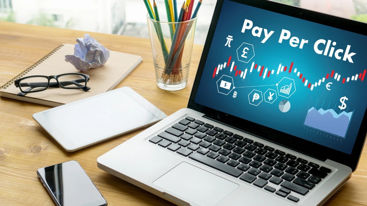 Laptop screen displaying a Pay Per Click (PPC) dashboard with charts and financial symbols