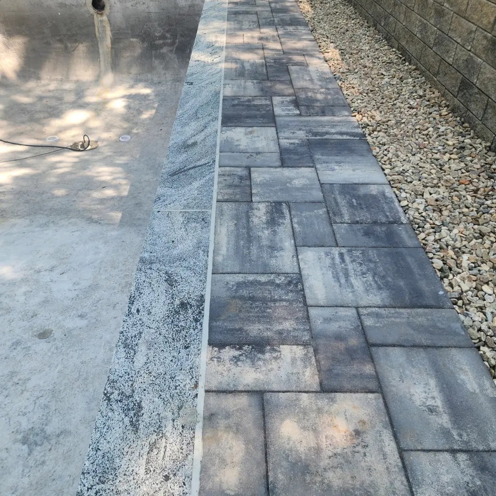 Pool coping and paver patio repair in Connecticut with new stone coping and gray paver installation