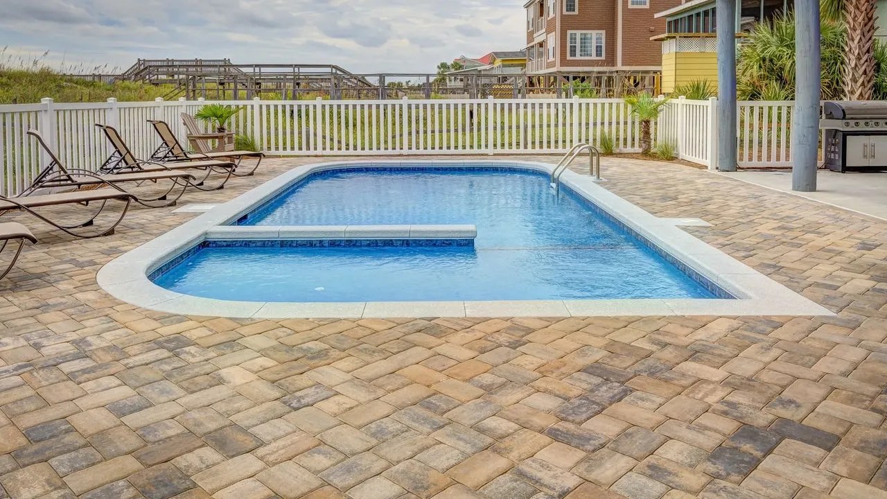 Inground pool bordered by paver coping and deck