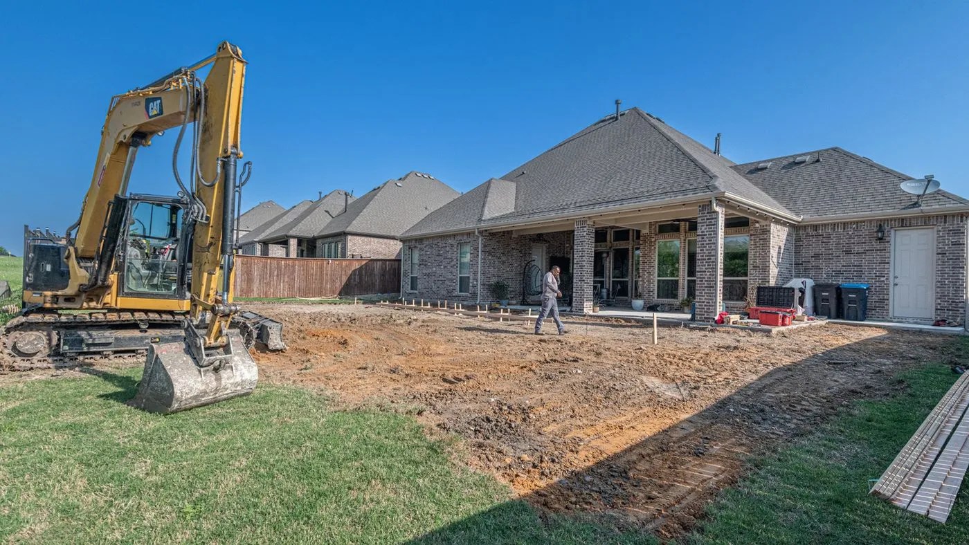 Excavator working in a suburban backyard before construction