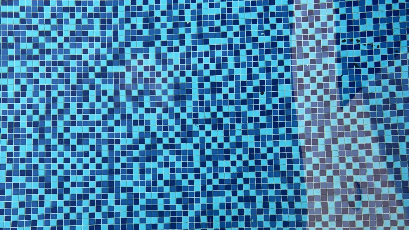 Blue mosaic tiled pool interior with a stainless ladder