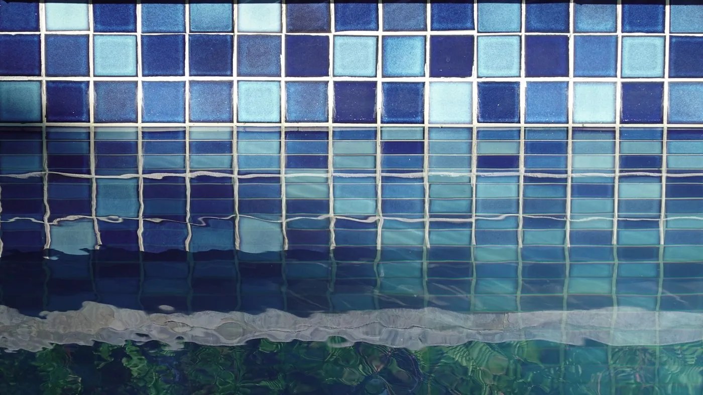 Blue mosaic waterline tile above clear pool water