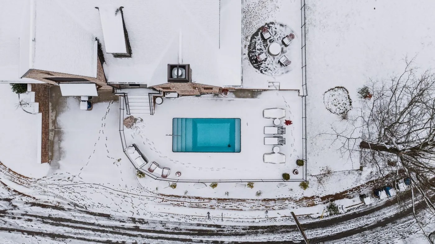 Aerial view of a backyard pool surrounded by winter snow