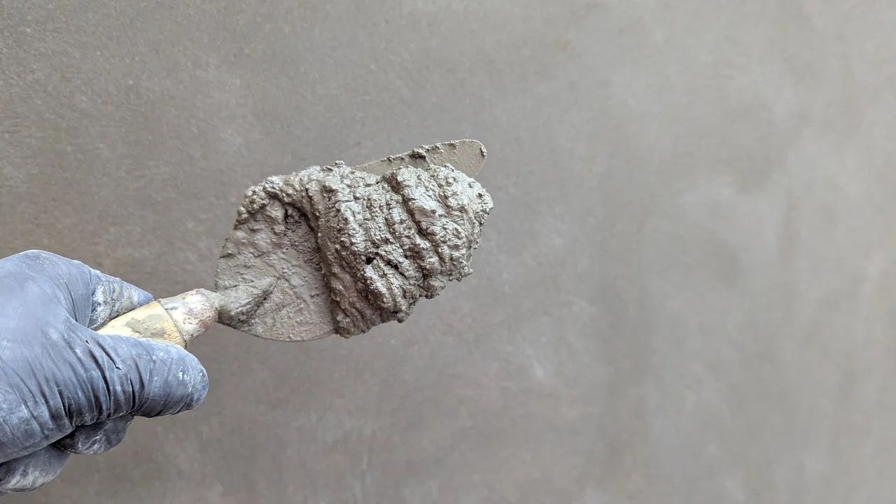 Trowel applying fresh plaster to a concrete surface