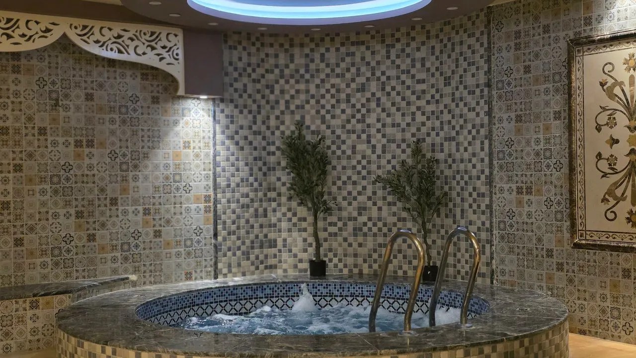 Mosaic tiled spa with curved bench and warm lighting