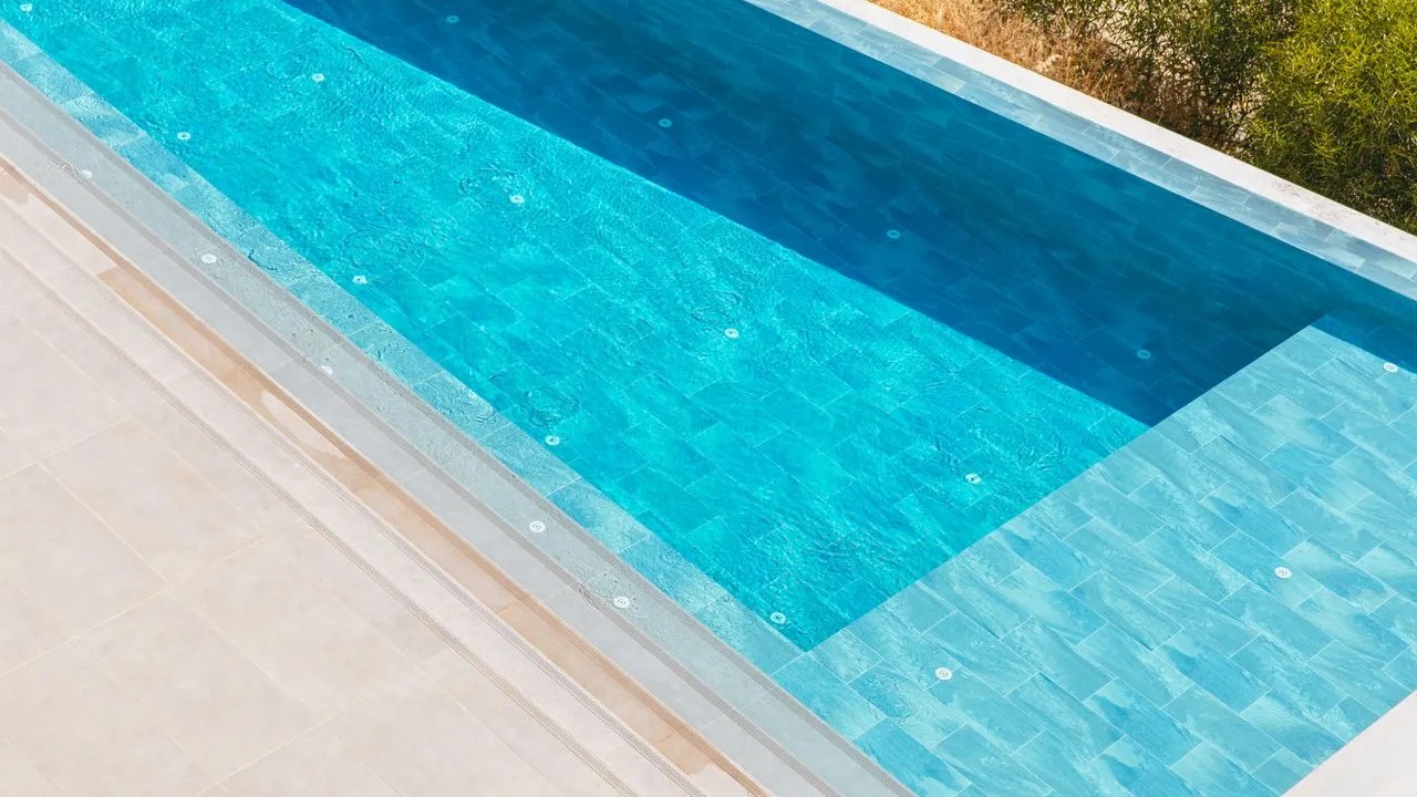 Aerial view of a renovated pool with new waterline tile and stone deck